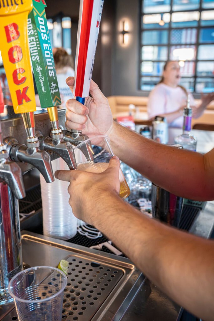 Bartender pouring cold beer from tap handles into a cup at the bar counter at The Bench Fort Worth