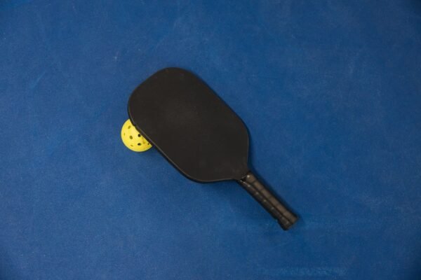 Pickleball paddle and yellow ball resting on a blue indoor court surface at The Bench Fort Worth