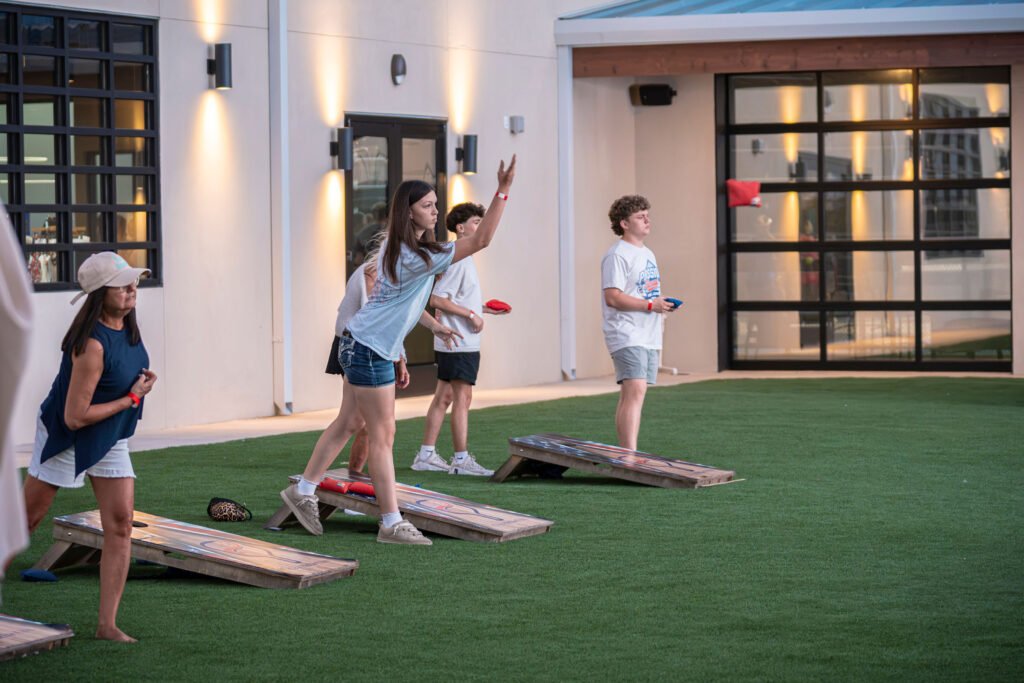 People playing cornhole on the artificial turf patio at The Bench sports bar in Fort Worth